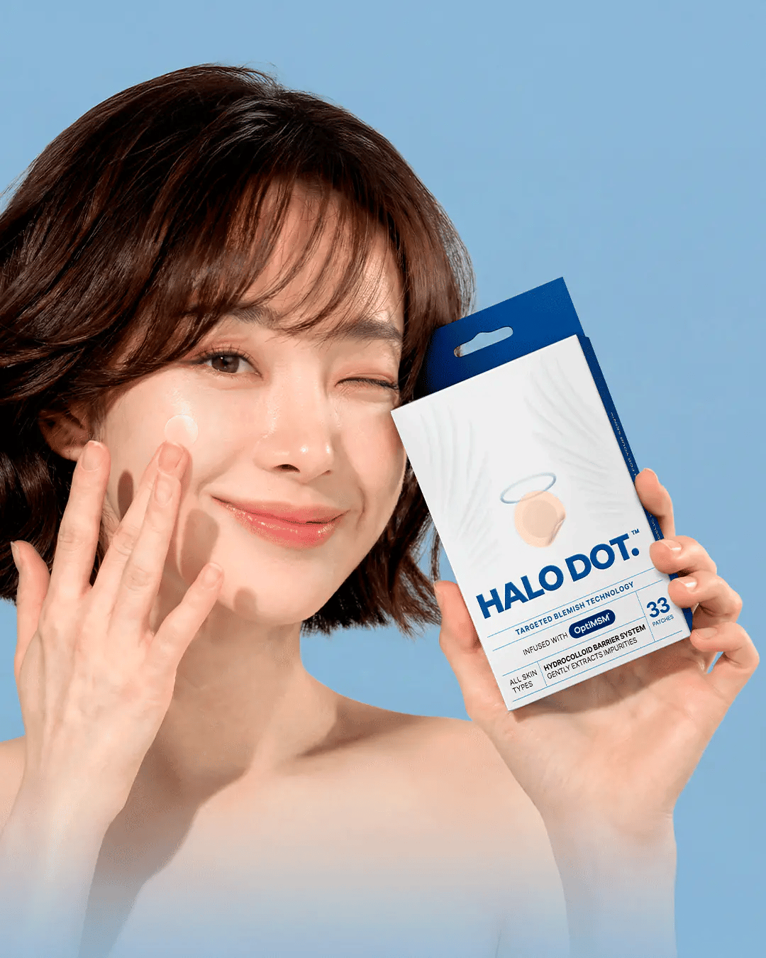Model applying a Halo Dot pimple patch while holding the 33-count package